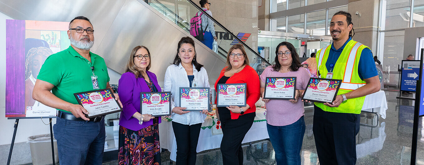 Group photo of METRO employees holding certificates of participation for sharing their art work to celebrate Hispanic Heritage Month.