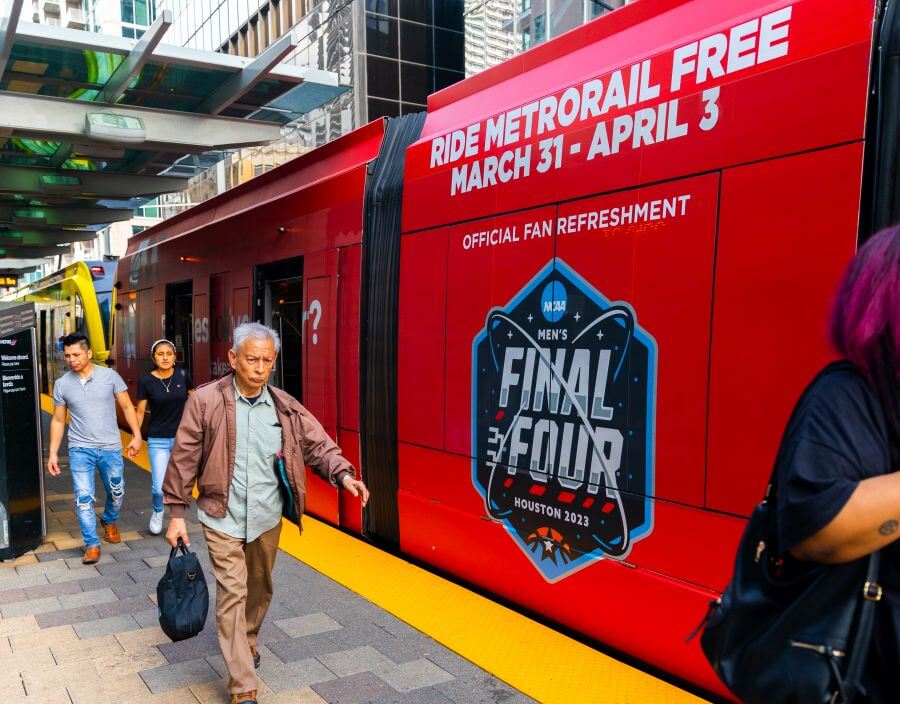 Riders exiting the train on the platform. The Red Line train is wrapped to promote free rides during the Final Four..