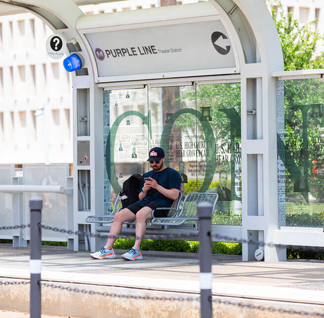 6846-rider-waiting-at-Rail-platform-656X643 Rider sitting down looking at his phone waiting on train at the METRORail platform.