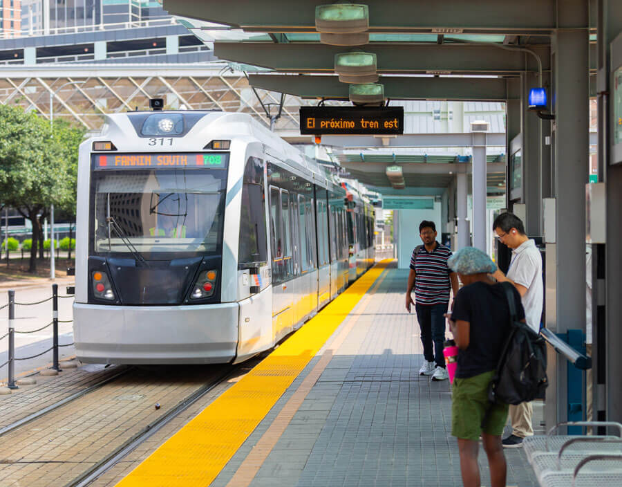 Customers waiting at rail platform to board incoming train.