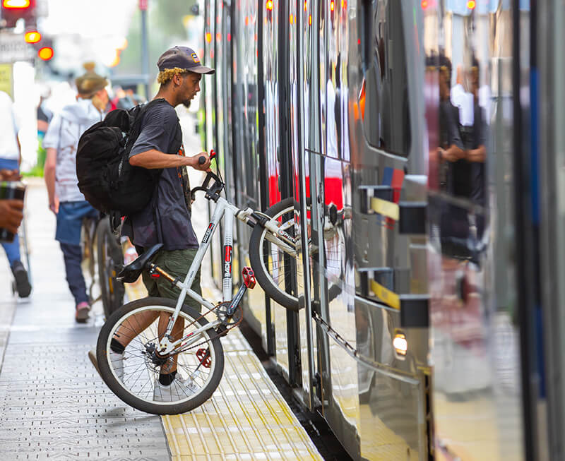 Rider rolling bike aboard a METRORail train.
