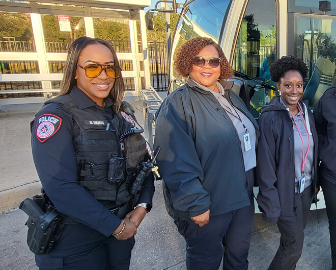 MPD C.A.R.E. Unit standing and smiling in front of a METRO local bus and bus shelter.