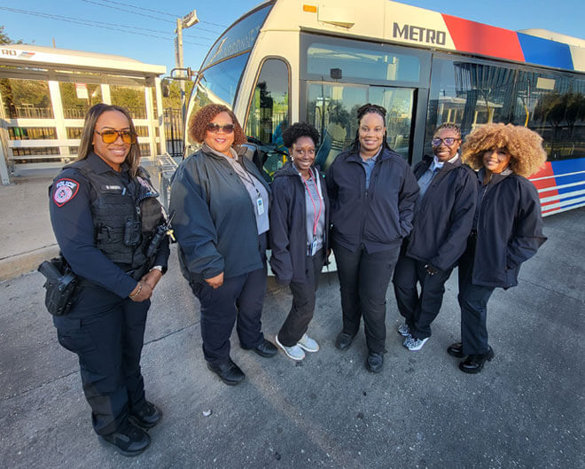 MPD C.A.R.E. Unit standing and smiling in front of a METRO local bus and bus shelter.