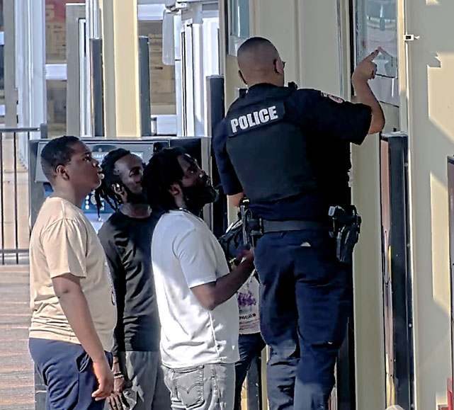 METRO Police Officer giving directions on the platform map to three METRORail riders.