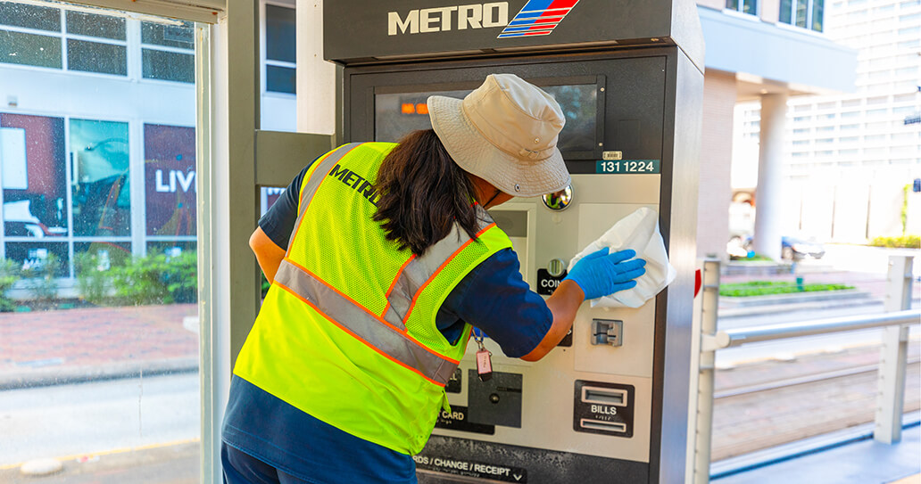 Ticket vending machine being wiped down and sanitized on METRORail platform.