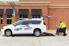 METROLift attendant assisting customer in wheelchair out of the back of a METROLift minivan