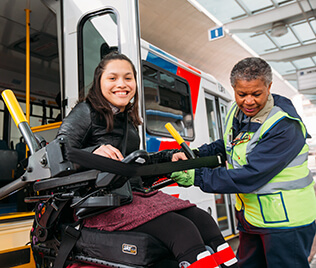 Passenger in wheelchair being secured by attendant inside METROLift van.