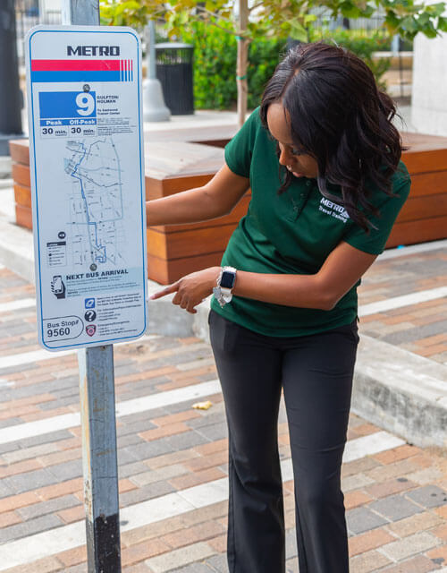 travel-trainer-reading-bus-stop-signage-500x640 Travel trainer pointing to and reading bus stop signage.