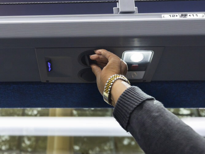 METRO customer adjusting the overhead air vent and reading light on a Park & Ride bus.
