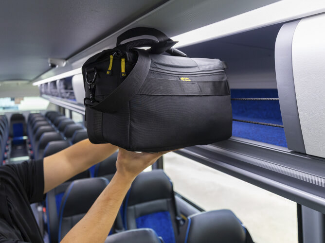 Customer placing a bag in the overhead storage bin on a Park & Ride bus.