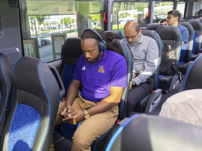 A customer with headphones on sitting in an aisle seat on a METRO Park & Ride bus.