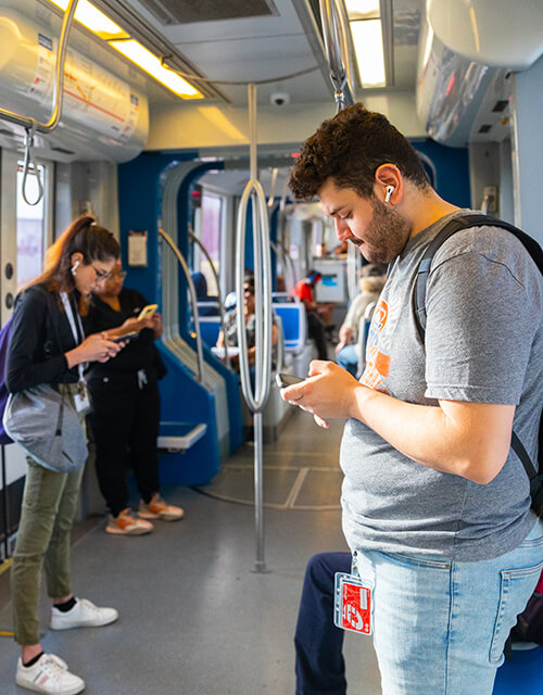 METRORail riders using headphones and looking at their phones.