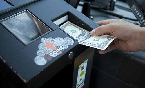 Customer paying their fare upon boarding by placing a dollar bill in the cash box.