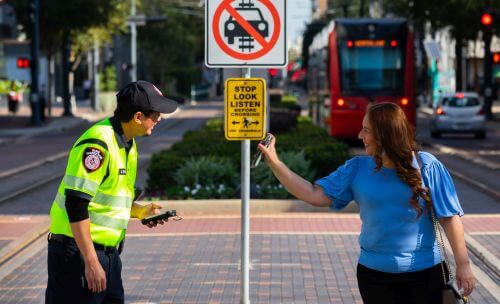 tramway tours hopital Customer displaying smartphone for fare inspector along the METRORail Red Line