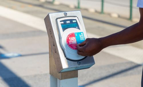 Rider tapping a METRO Day Pass on a fare validator on a METRORail platform.