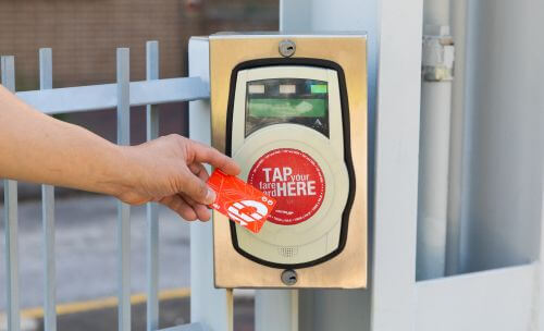 Rider waving a METRO Q Fare Card at a fare validator on a METRORail platform.