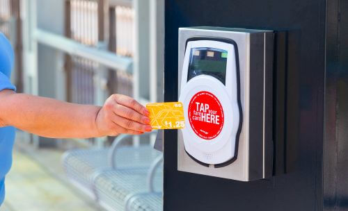 Rider waving a METRO Money card at a fare validator on a METRORail platform