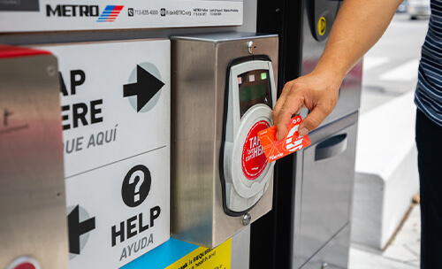 Rider tapping a METRO Q® Fare Card on METRORapid Silver Line platform fare validator.