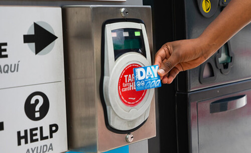 Rider tapping a METRO Day Pass on a METRORapid Silver Line platform fare validator.